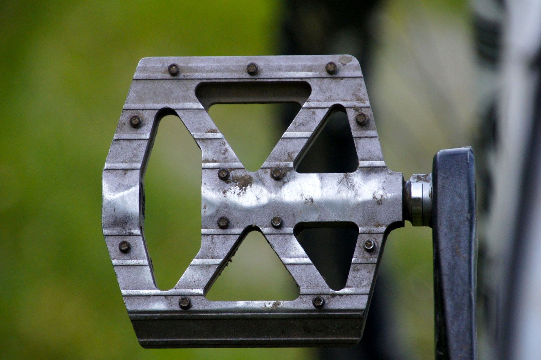 Close-up of a worn silver flat bicycle pedal with traction pins.
