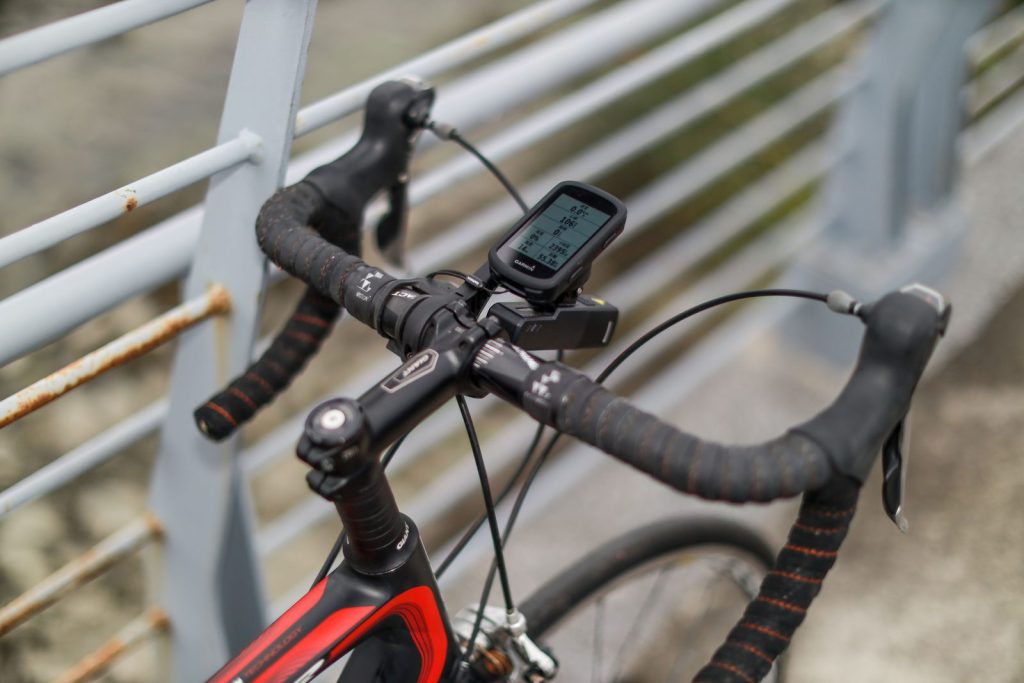 GPS bike computer on an out-front mount on drop handlebars, with a front light mounted underneath.